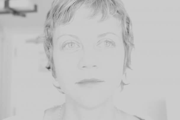Black and white overexposed headshot of Libby Spears from the neck up with a neutral expression and a pixie haircut.