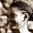 Elinyisia Mosha looking away from the camera. She has braided dreadlocks in a low bun and is wearing earphones. Portrait in sepia.