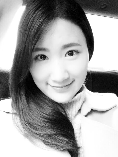 Danni Wang looking directly ahead. She has long dark hair and wears a light-colored top. Black and white portrait.
