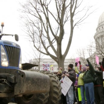 People in a demonstration in DC. They are standing in front of a tractor.