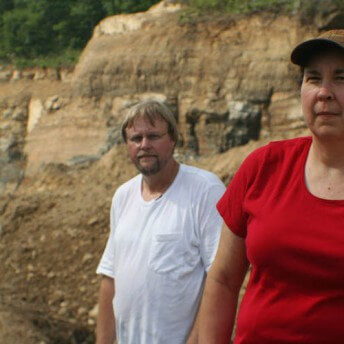 A man and a woman standing in front of a mountain ridge.