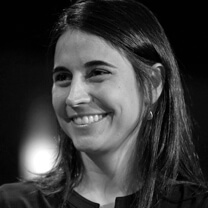 Julia Bacha looks away from the camera and smiles. She has medium-length hair. Portrait in black and white.