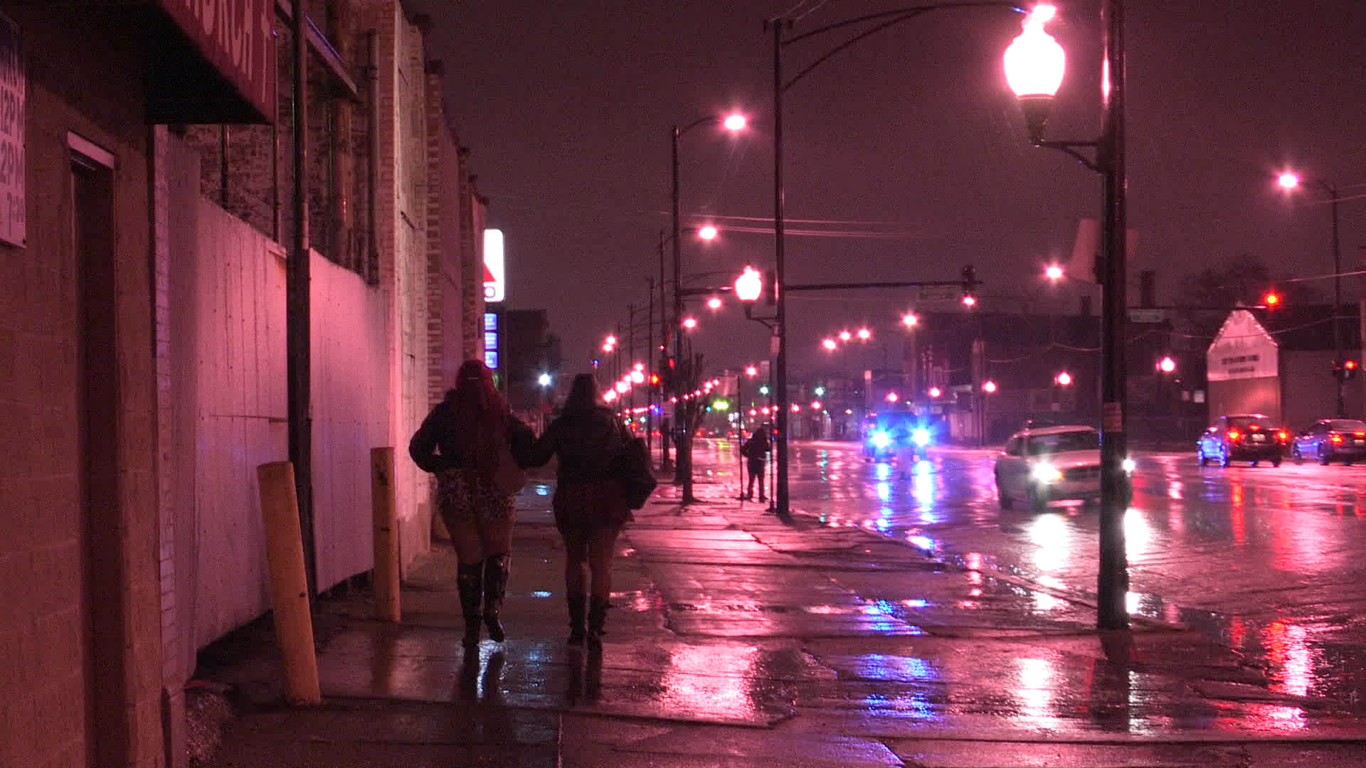 Two people walking in a street at night.