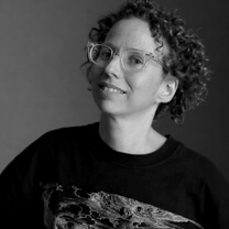 Jennie Livingston looks at the camera and smiles. She wears eyeglasses. Portrait in black and white.