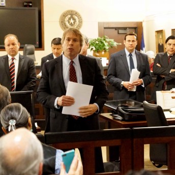 Still from Southwest of Salem. A man in a suit addresses the court, behind him there are six persons in a suit.