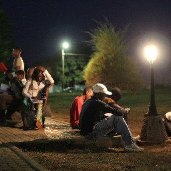 Young people are reading during the night with street lightning.