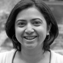 Vaishali Sinha is looking directly at the camera, smiling. Black and white portrait.