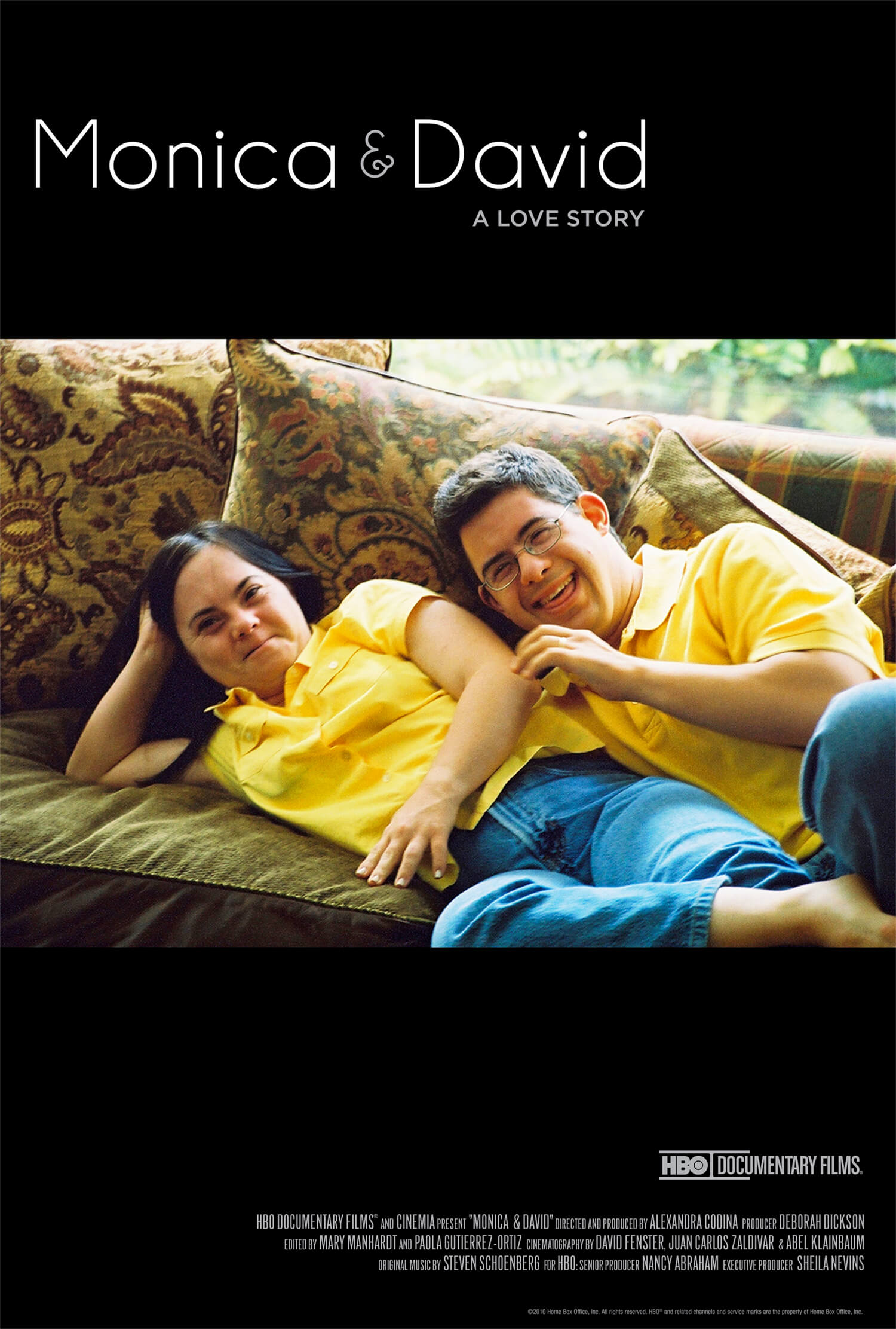 Poster from Moica & David. Below text that reads, "Monica & David A Love Story" are two people wearing yellow polo shirts and jeans laying next to eachother on a couch with floral pillows. They are both smiling. Film credits are listed on the poster below the couple.