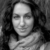 Sasha Friedlander looking straight ahead. She has wavy, dark, shoulder-length hair and is wearing a scarf. Black and white portrait.
