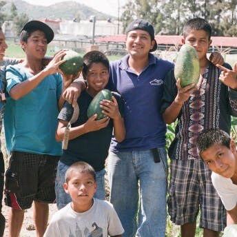 Still from Visitor's Day. A handful of young men and boys stand posing for the camera, some are holding watermelons.