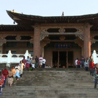 Two lines of people coming out of a Buddhist temple.