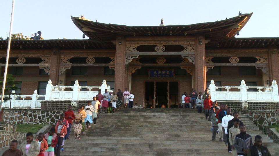 Two lines of people coming out of a Buddhist temple.