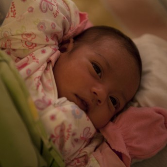 Still from Tough Love. Close-up of a baby that is covered in blankets and wearing gloves.