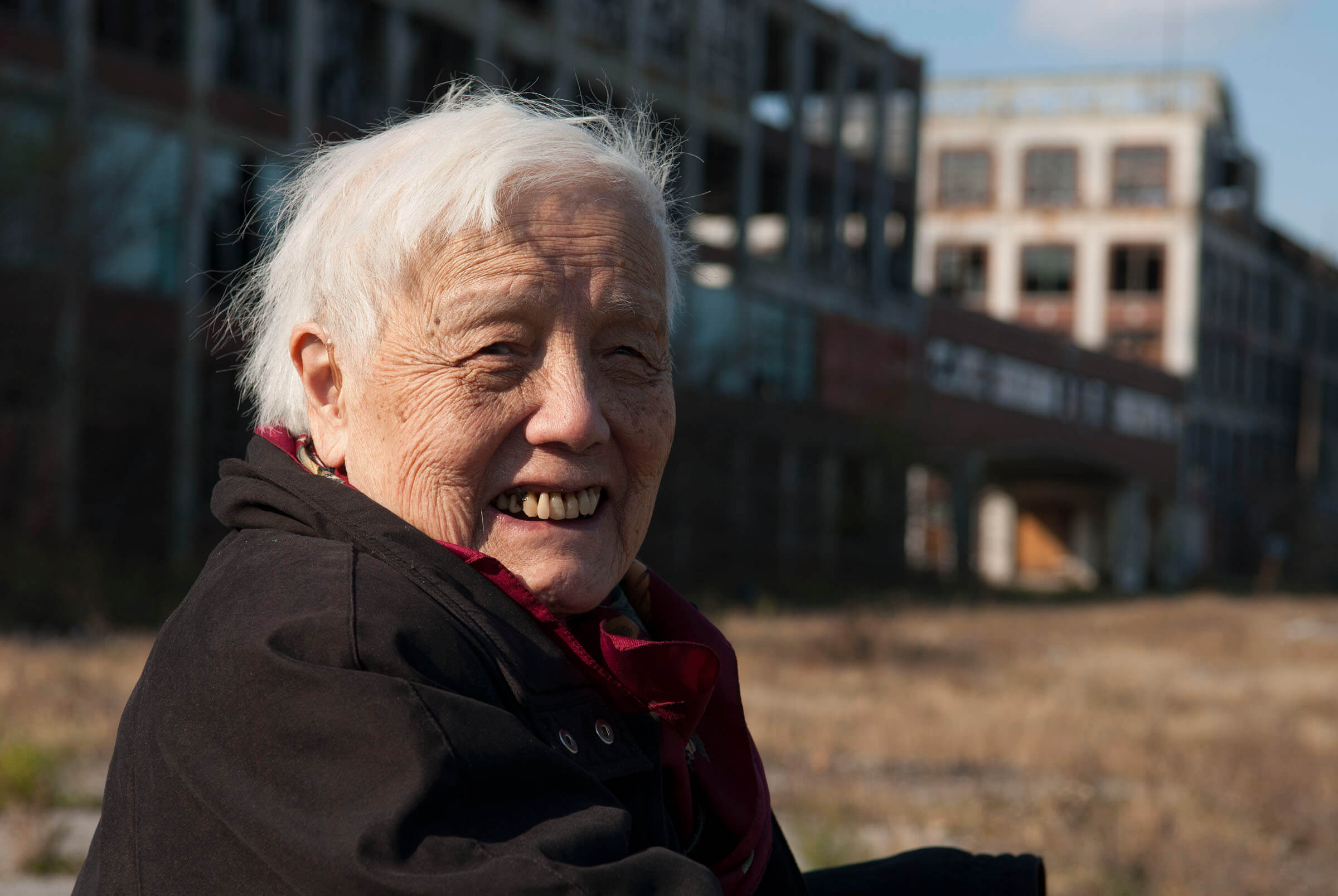 Stil from Grace Lee American Revolutionary: The Evolution of Grace Lee Boggs. Grace Lee Boggs is looking directly at the camera and smiling, she has white short hair, and is wearing a black warm jacket.