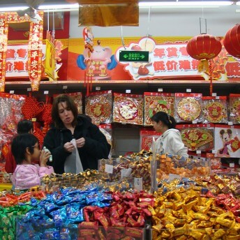 Donna Sadowsky and Sui Yong in a store filled with Chinese decorations and brightly wrapped candies. Color photograph.