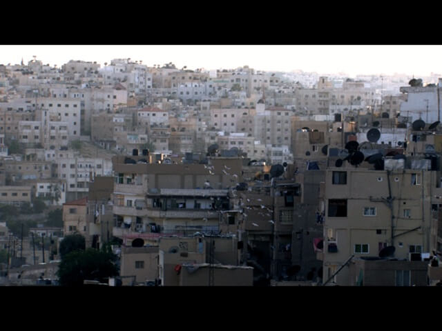 Still from Between Earth & Sky. A full shot of a crowded urban development.