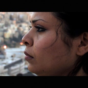 Still from Between Earth & Sky. Profile shot of a woman looking away from the camera. She is wearing dark red lipstick.