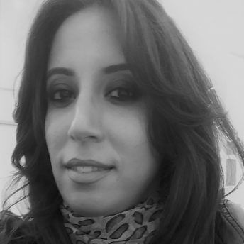 Hiba Dhaouadi looking straight ahead. She has long dark hair, and wears a patterned scarf. Black and white portrait.