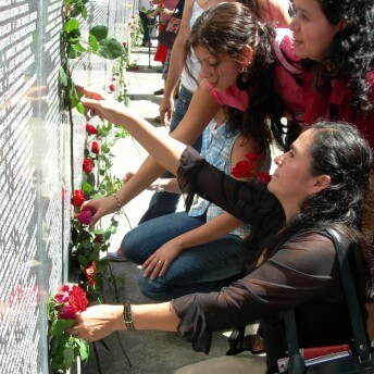 Women placing flowers on the wall that commemorates the missing children of the civil war in El Salvador.