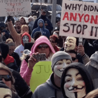 Still from Roll Red Roll. A crowd of people, some with Anonymous group masks on, are gathered. There is a sign that reads, "Why didn't anyone stop it?".