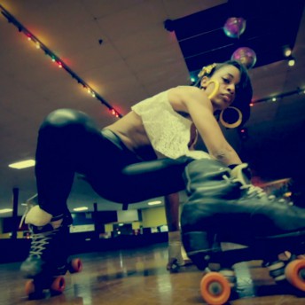 Still from United Skates. A woman in skates on a skating rink is doing a move near the floor in front of the camera.