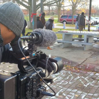 A cameraman filming people in the park.
