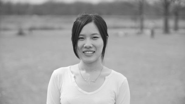 Black and white headshot of Siyi Chen from the chest up wearing a white shirt outside in a field