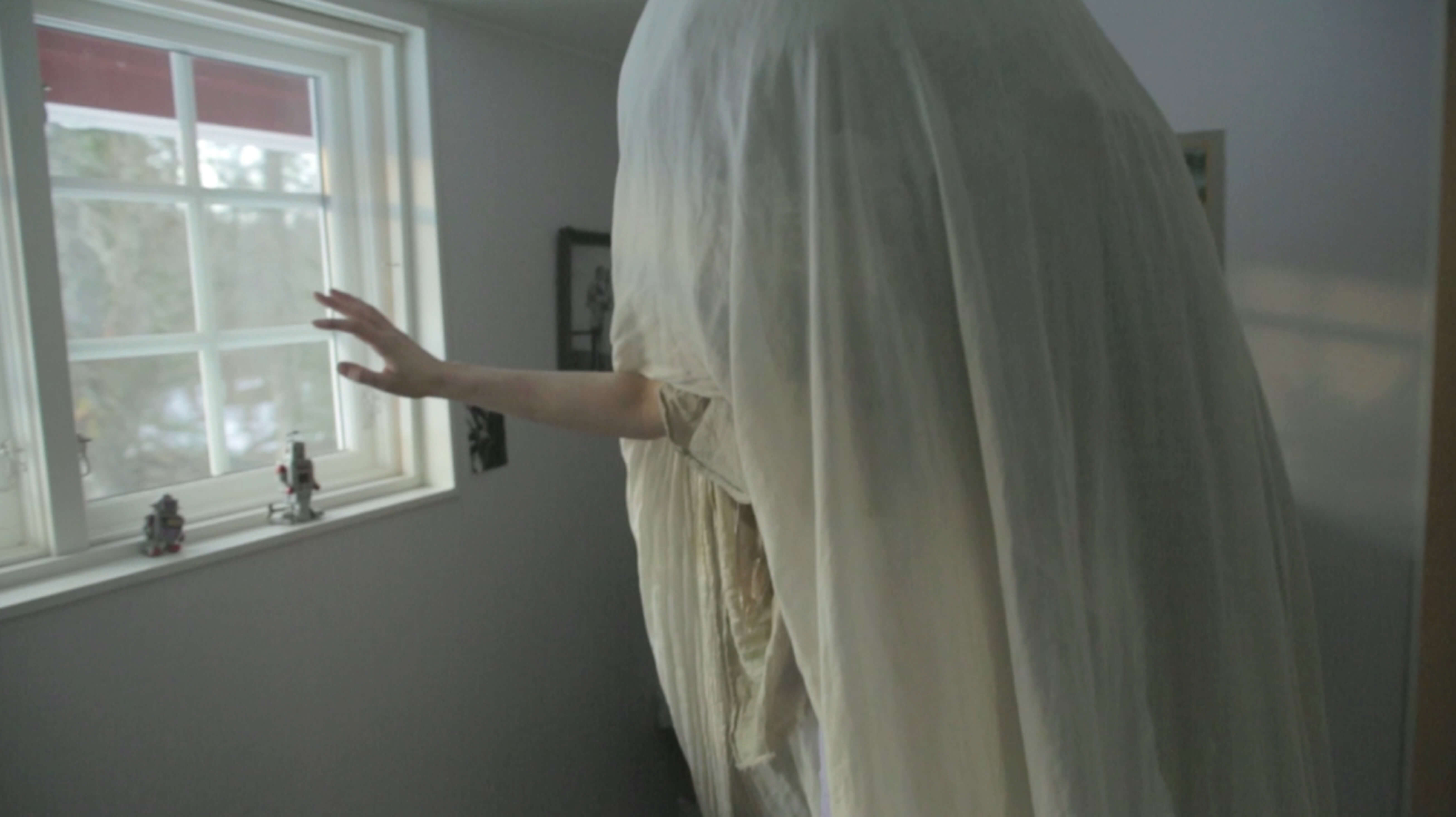 A person under a white sheet extends an arm out.