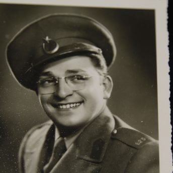 Still from A Prince from Outer Space: Zeki Muren. An old, sepia-toned, photograph of a man wearing glasses and a military uniform, he is smiling and looking off-camera.