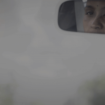 A rearview mirror with the reflection of a woman.