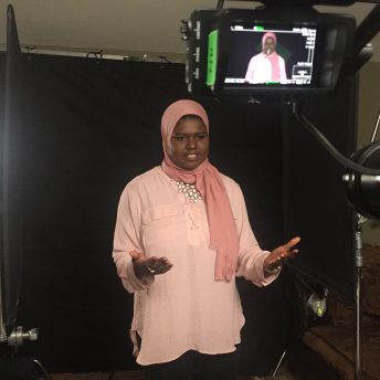 Production still of An Act of Worship. Khadega Mohammed is speaking in front of a camera in a studio.