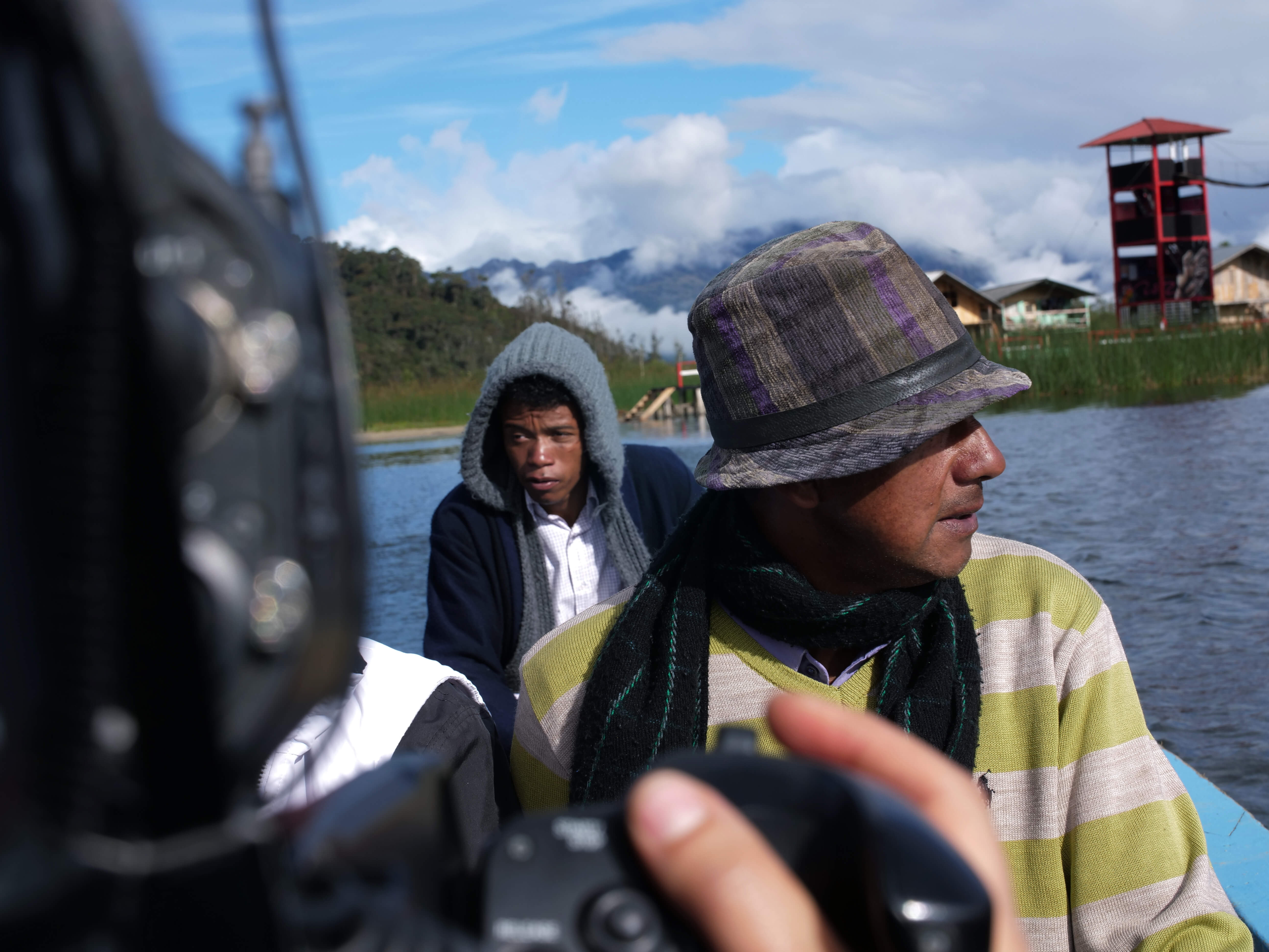 Production still of Paths of Fire. Over the shoulder shot of three men traveling on a boat, they are wearing warm clothing.