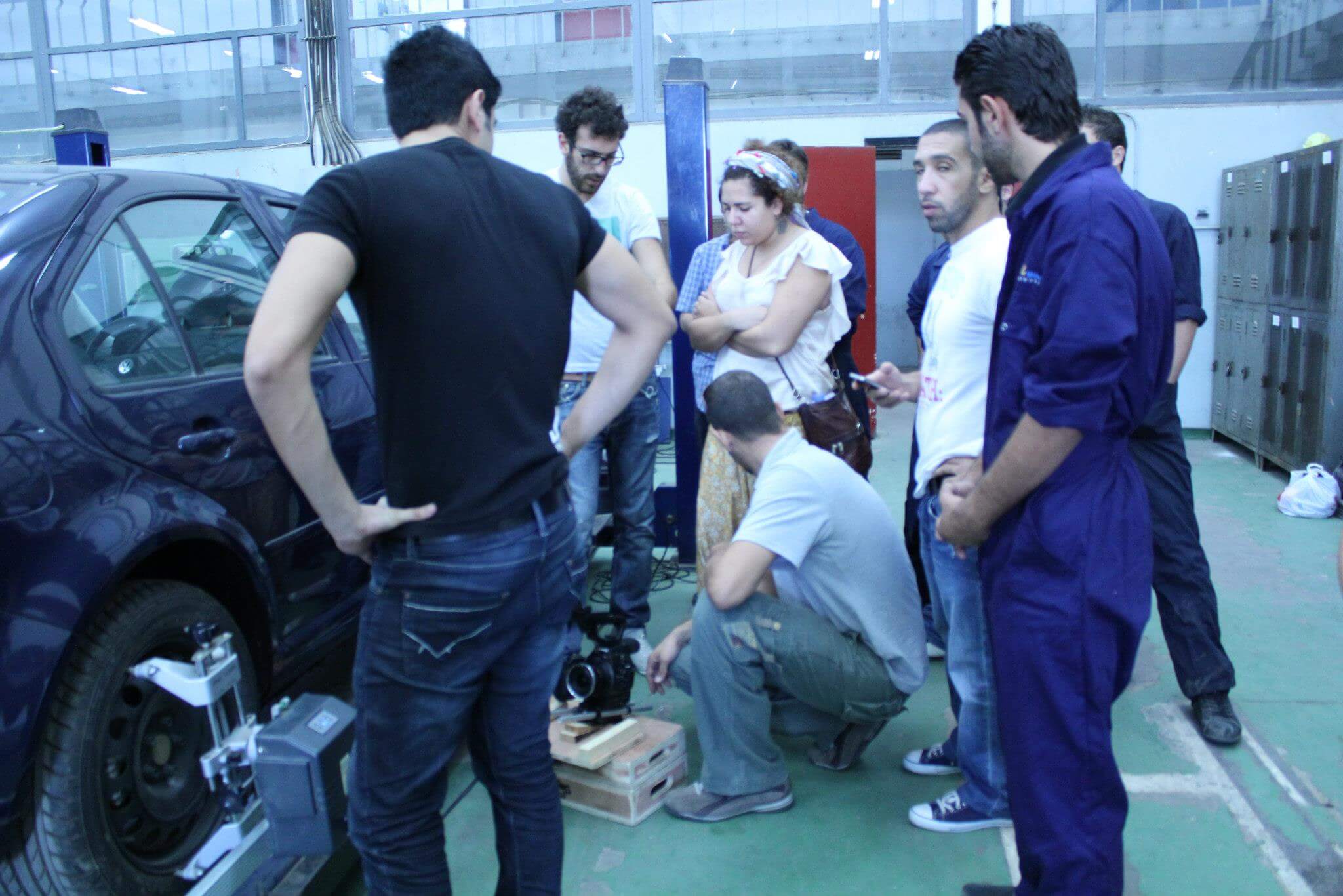 A group of people standing next to a car. Color photograph.