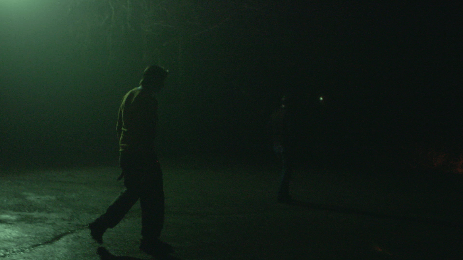 Still from Storming. A person walks on a dark road.
