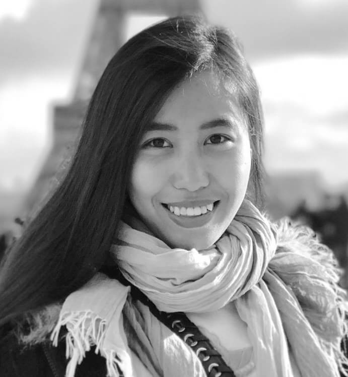 Snow (Hnin Ei Hlaing) is smiling at the camera, the Eiffel Tower is behind her. Black and white portrait.