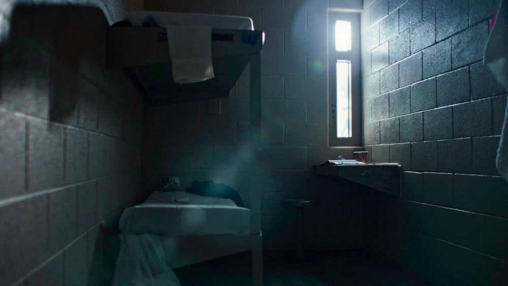 Still from Belly of the Beast. Interior of a cell. There is a bunkbed and a lavatory.