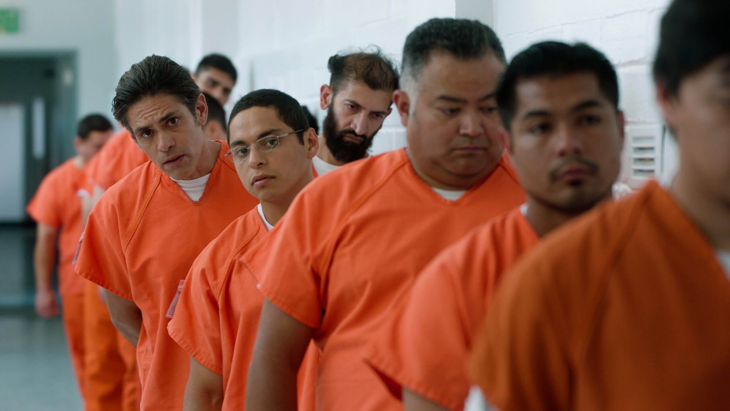 Men in orange prison uniforms are in a line.