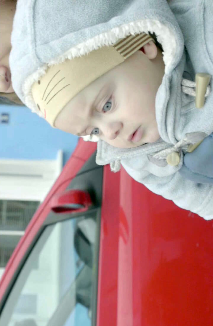 Still from Is There Anybody Out There? Close-up of Ella Glendining's infant son River. He is wearing a hat and a thick light blue coat.