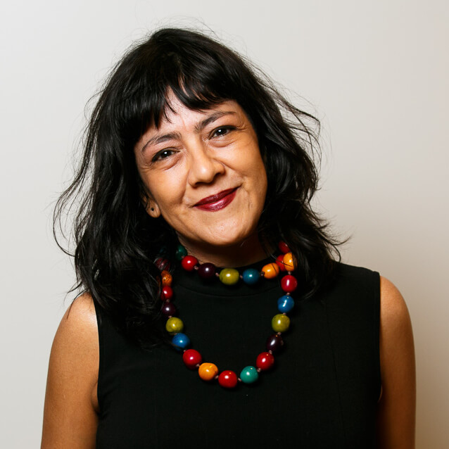 Headshot image of Lucila Moctezuma. Lucila is a Mexican woman with long black hair and a colorful necklace.