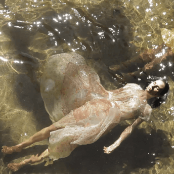 Aerial shot of two women swimming in clear water, wearing nightgowns