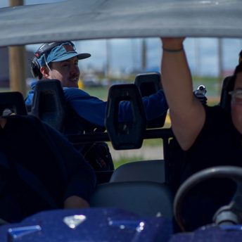 The directors of when they were here sitting in a side by side vehicle shooting in the summer of 2021 on the Blackfeet Reservation. Their sound engineer Colter Olmstead is seen the background.