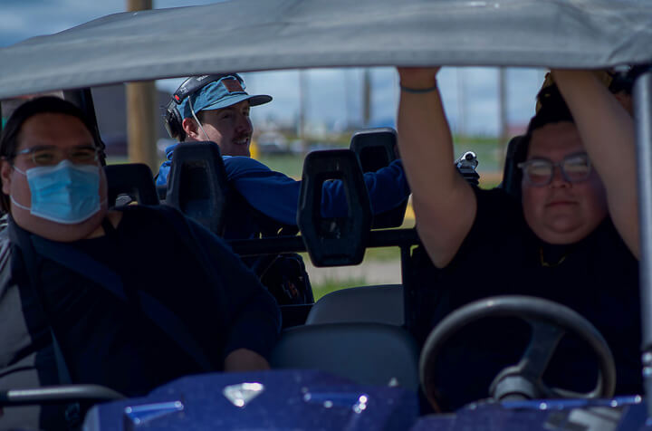 The directors of when they were here sitting in a side by side vehicle shooting in the summer of 2021 on the Blackfeet Reservation. Their sound engineer Colter Olmstead is seen the background.