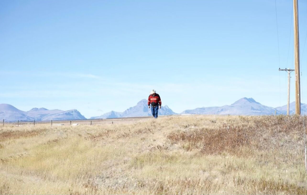 Kenny Still Smoking is seen walking in the foreground near a place, on the Blackfeet Reservation, where he searched for his daughter Monica when she went missing.