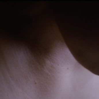Close up to the neck and chin of a woman looking downwards