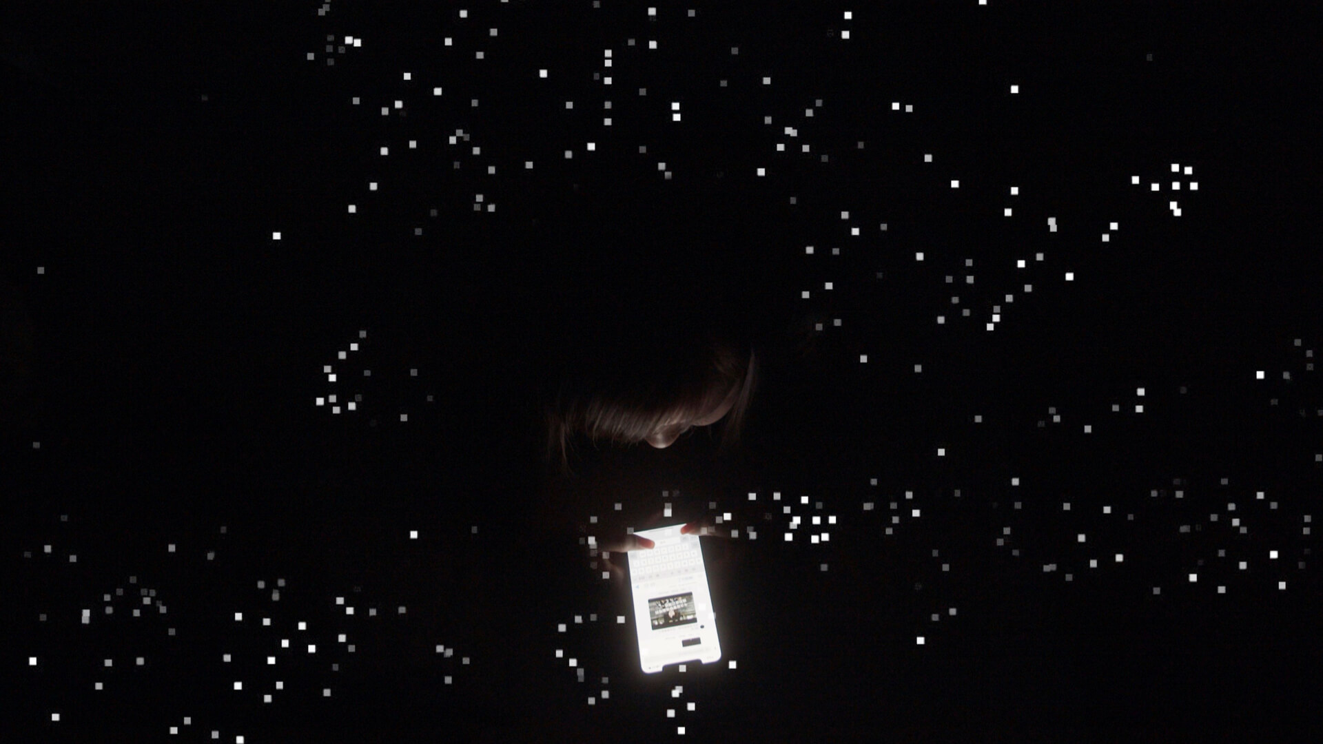 Aerial shot of a woman golding a cellphone, surrounded by little lights