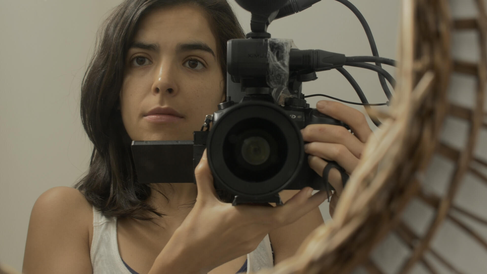 A woman holding a camera in front of a mirror with the mirror's frame visible
