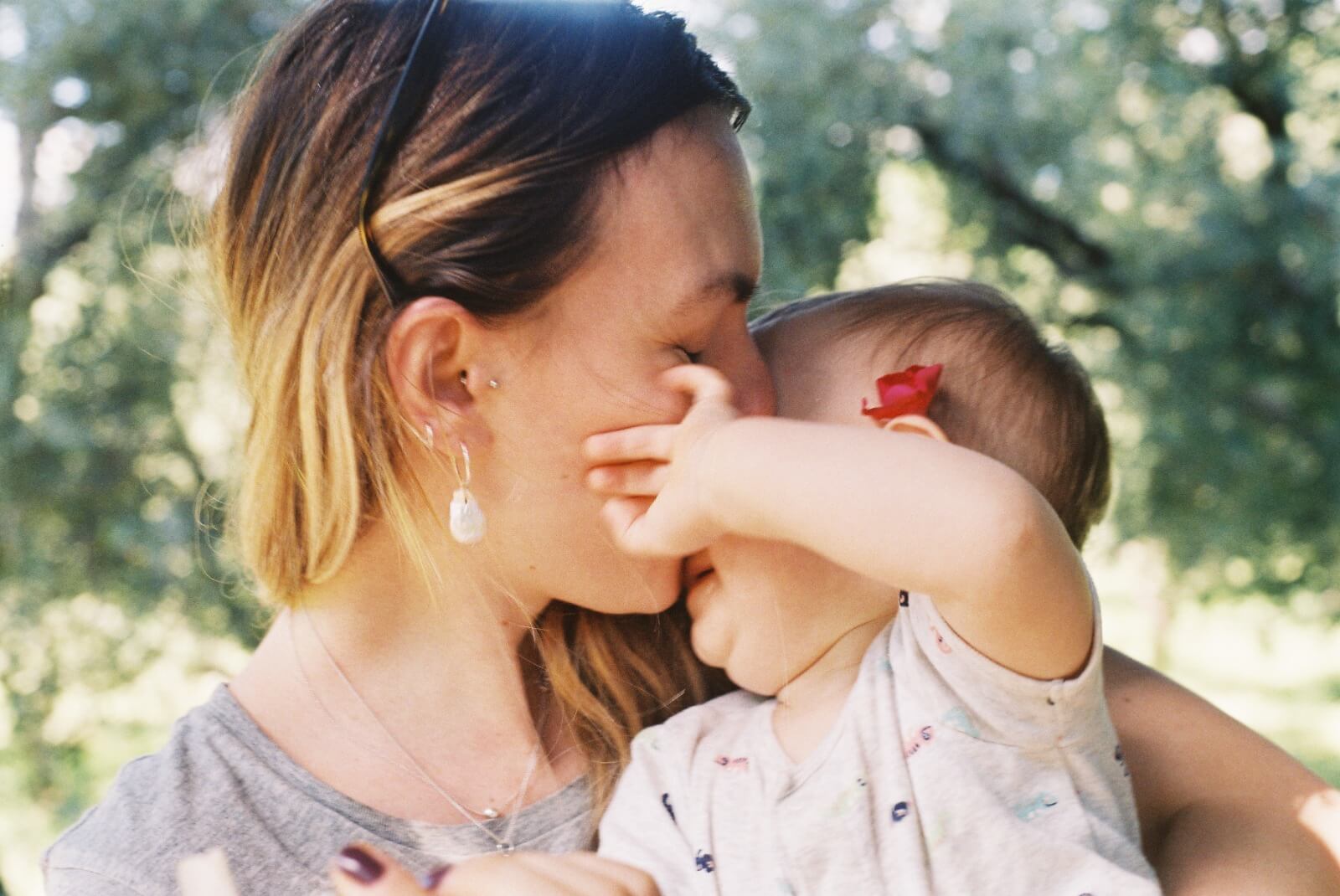 Lina is kissing her baby daughter on the forehead.