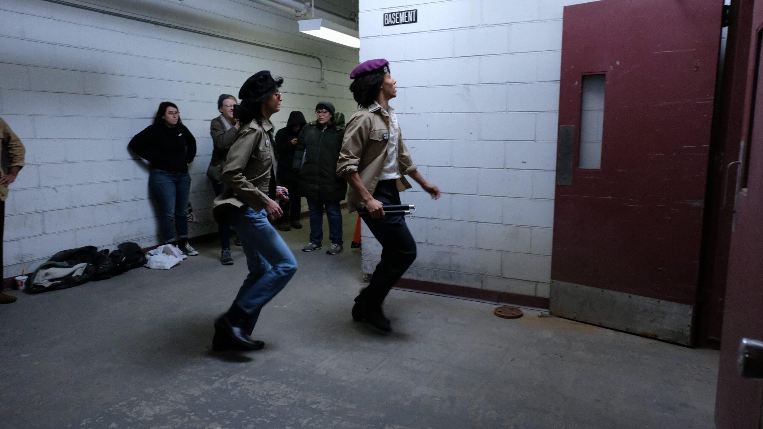 Two actors dressed as members of the Young Lords Party walking very fast