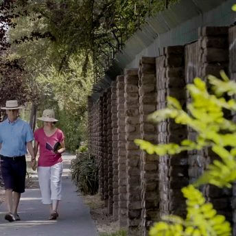 Still from The Eternal Memory. Augusto and Paulina holding hands and walking down a lane, both wear hats.