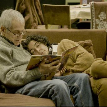 Still from The Eternal Memory. Augusto and Paulina reading from a magazine on a sofa.